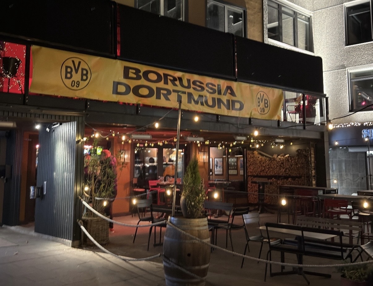 Gelbes BVB Banner hängt über einer beleuchteten Kneipe