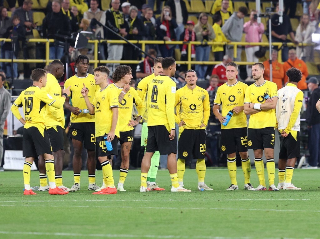 Eine Gruppe von Spielern des BVB steht niedergeschlagen zusammen